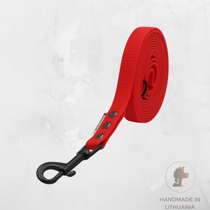 A bright red dog leash with a black metal clip, shown coiled on a light gray textured background with a 'Handmade in Lithuania' logo in the bottom right corner.
