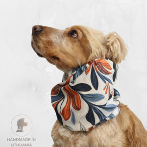 Golden Cocker Spaniel wearing an Autumn Bloom waterproof dog snood with cream, navy blue, grey and orange botanical leaf pattern.