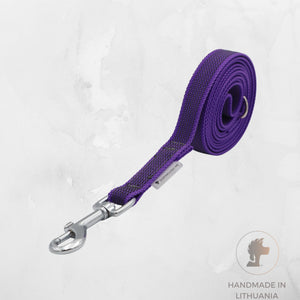 A purple woven dog leash with a silver metal snap hook and ring, shown coiled on a light gray textured background with a 'Handmade in Lithuania' logo in the bottom right corner.