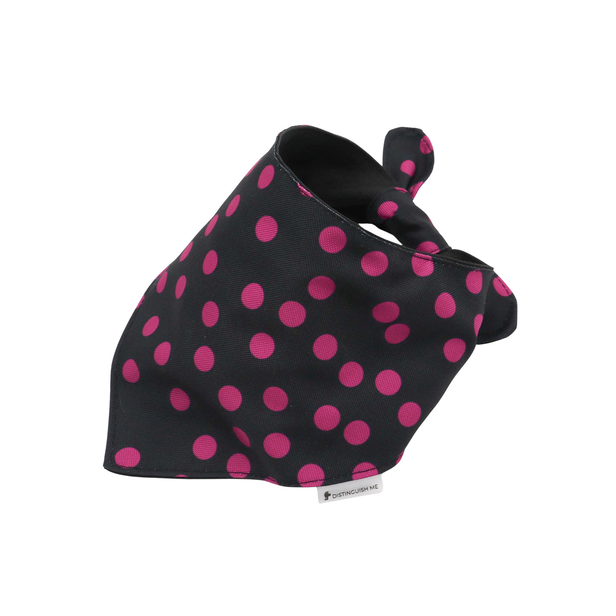 A black pet bandana with a vibrant pink polka dot pattern, featuring a small white brand tag at the bottom edge, set against a plain white background.