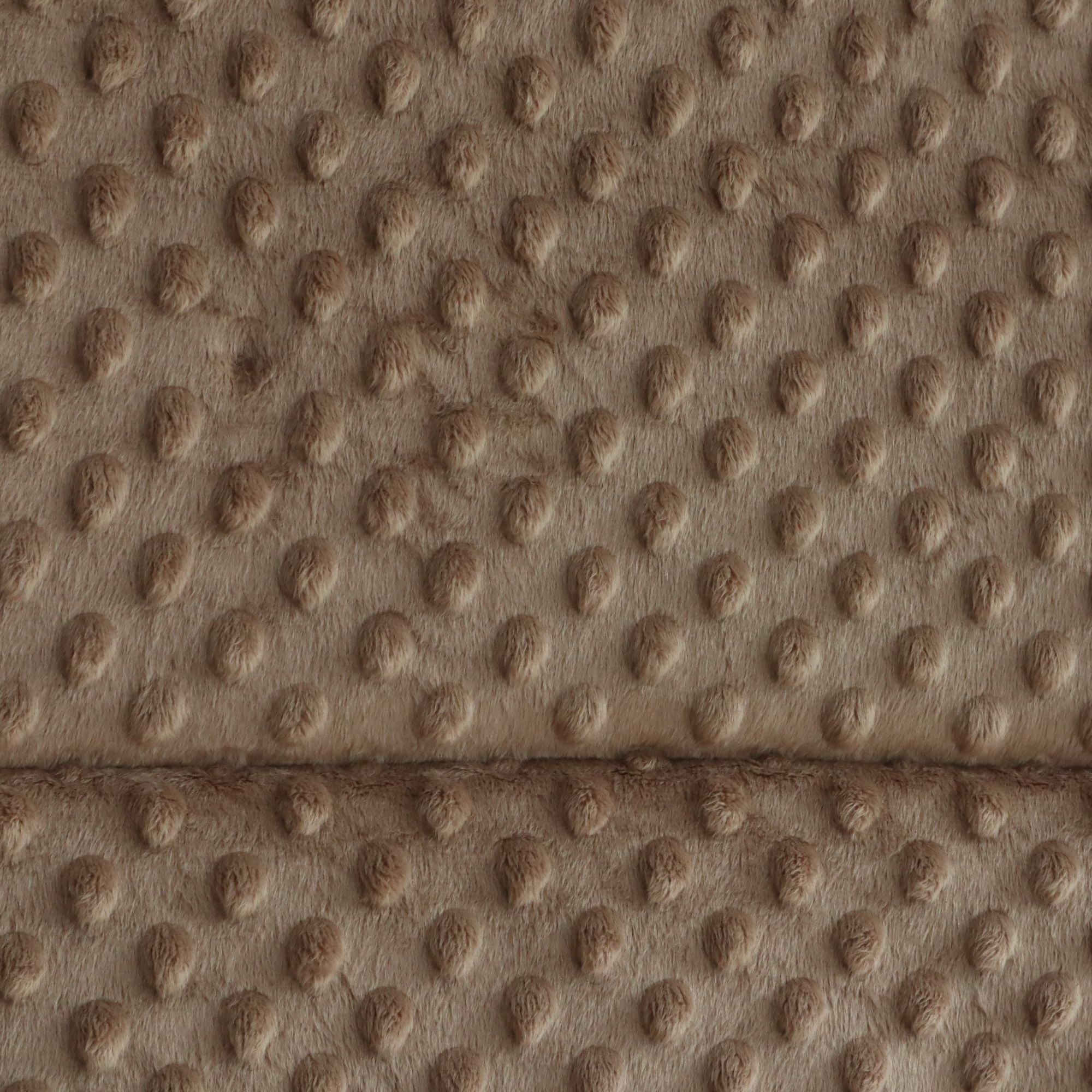 Close-up of a textured faux fur or microfiber fabric with a raised circular dot pattern in warm taupe and brown tones.