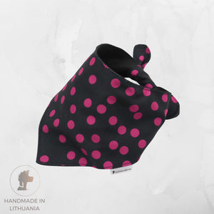 A black pet bandana with bright pink polka dots, shown on a light gray textured background. A small white tag with the brand name 'PENGUINDOG' is visible near the bottom edge.