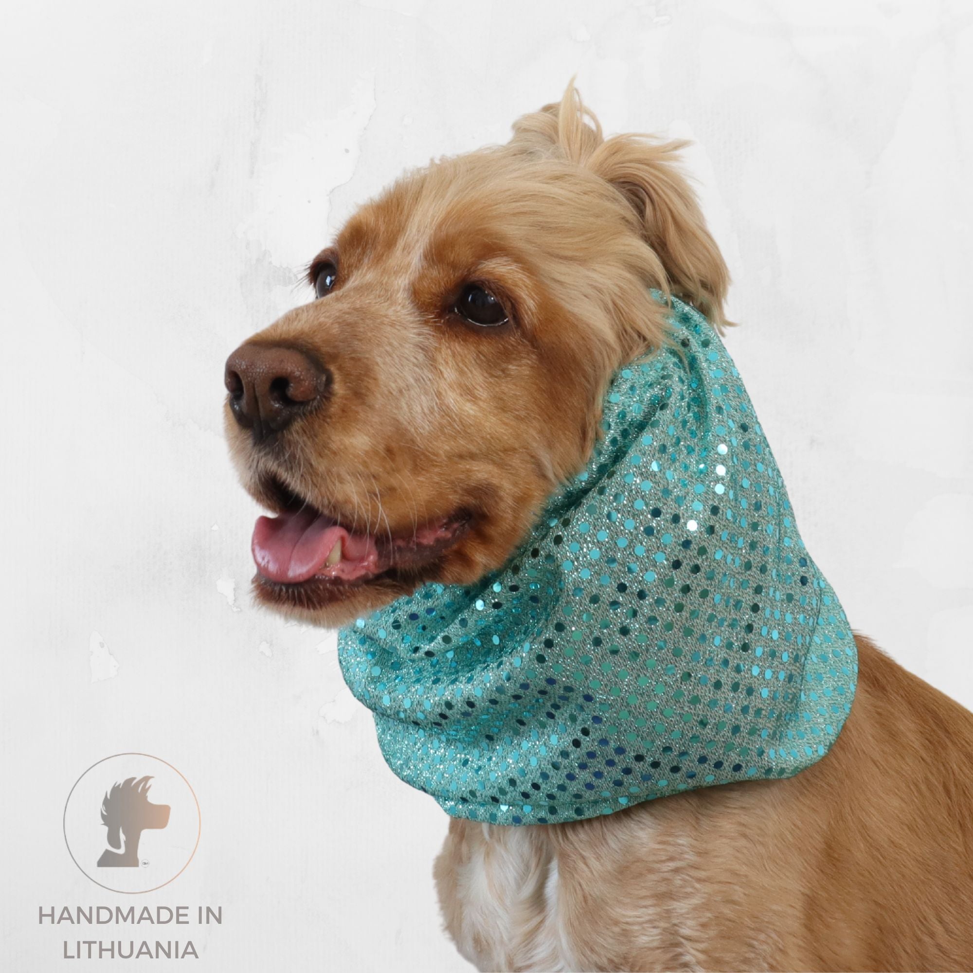 A golden dog wearing a sparkling teal sequined cowl neck warmer, shown in profile against a light textured background. A 'Handmade in Lithuania' logo is visible in the bottom-left corner.