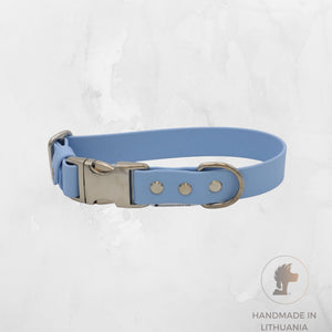 A light blue dog collar with a silver metal buckle, D-ring, and rivets, displayed on a light gray textured background with a 'Handmade in Lithuania' logo in the bottom right corner.