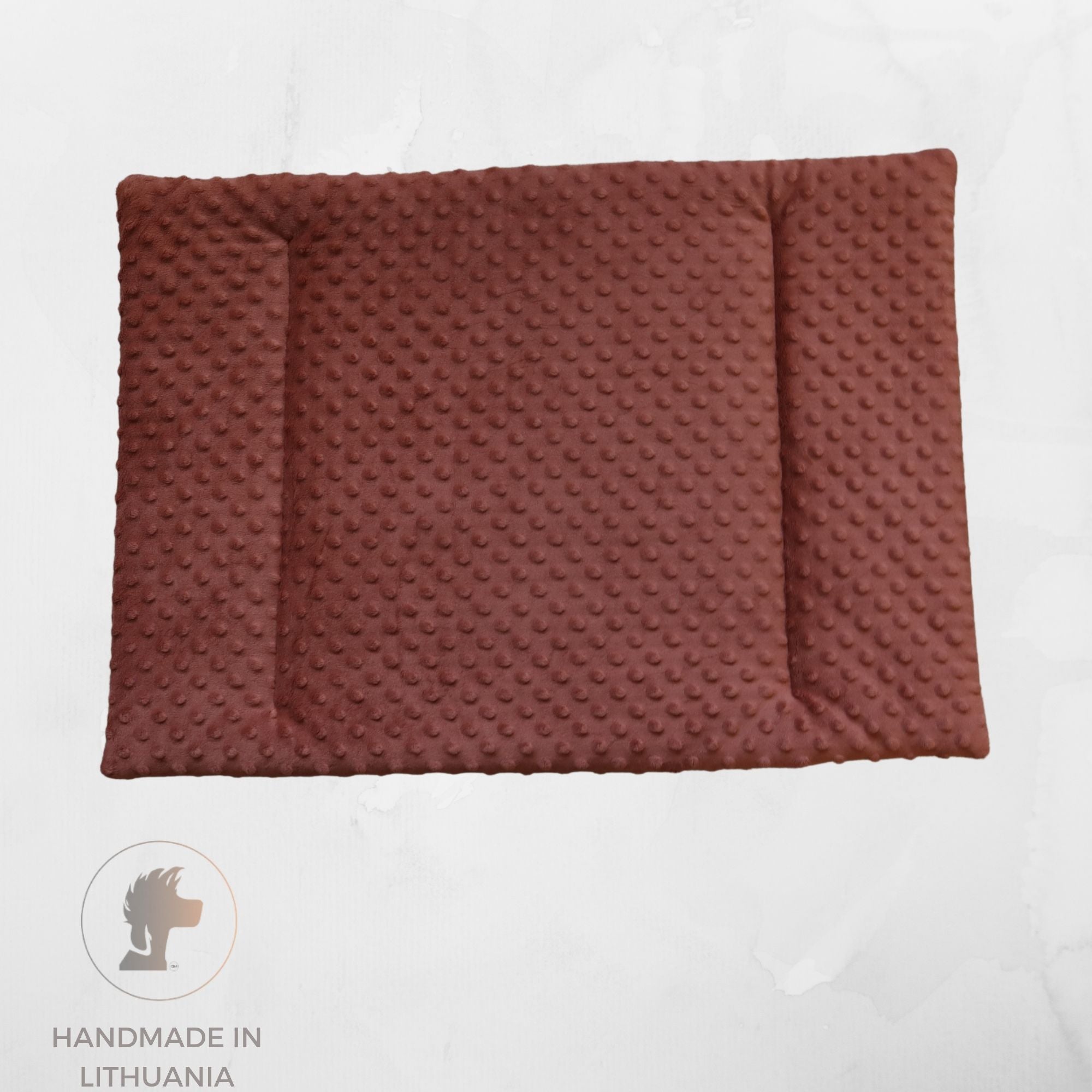 A rectangular brown textured pet mat with raised circular dots, shown from above on a light gray background. A circular logo at the bottom left reads 'HANDMADE IN LITHUANIA' with a stylized lion head icon.